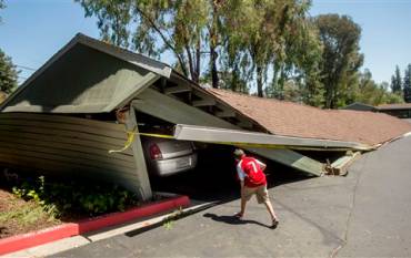 A boy looking at cars in a collapsed garage.