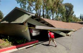 A boy looking at cars in a collapsed garage.