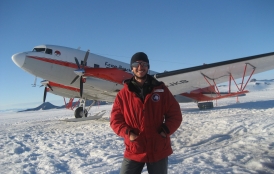 Dustin Schroeder stands in front of airplane in Antarctica