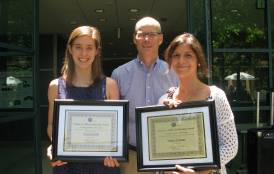 Three people standing with plaques 