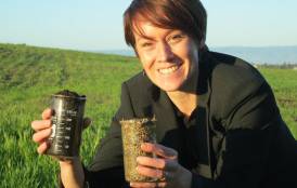 Kate Maher hold two beakers of soil.