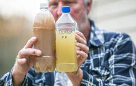 Ray Kemble holds two samples of well water from his neighborhood in Dimock, PA. 