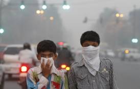 Two boys covering their mouths from the smog in India