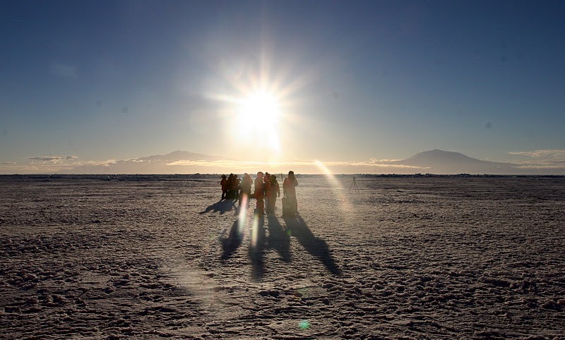 photo: a group of scientists take ice samples beneath a rising sun near the Ross Sea, Antarctica.