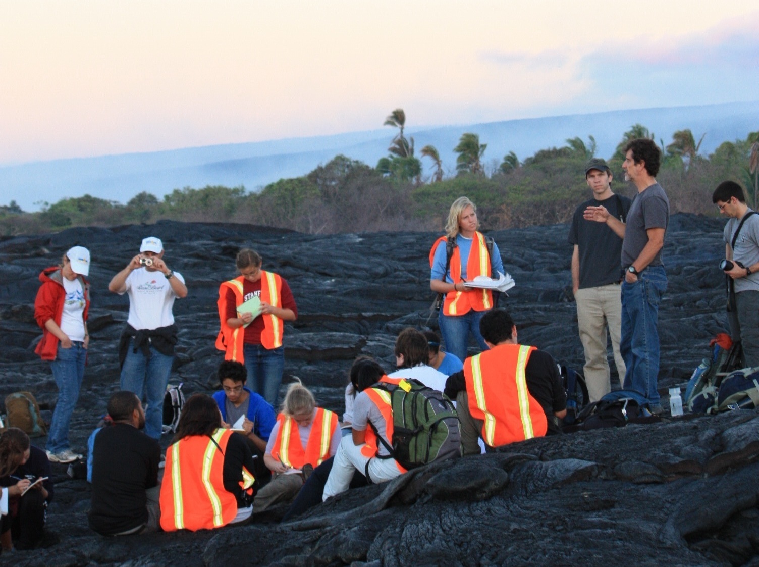 photo: Professor Paul Segall gives a lecture to a group of students at sunrise on the active lava flows on Kilauea volcano, Hawai'i