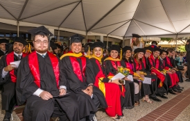 students seated at commencement in caps and gowns