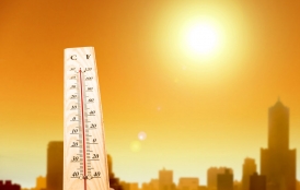 thermometer with bright sun and skyline in background